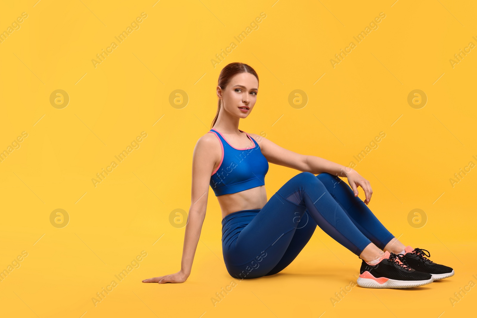 Photo of Young woman wearing sportswear on yellow background, space for text