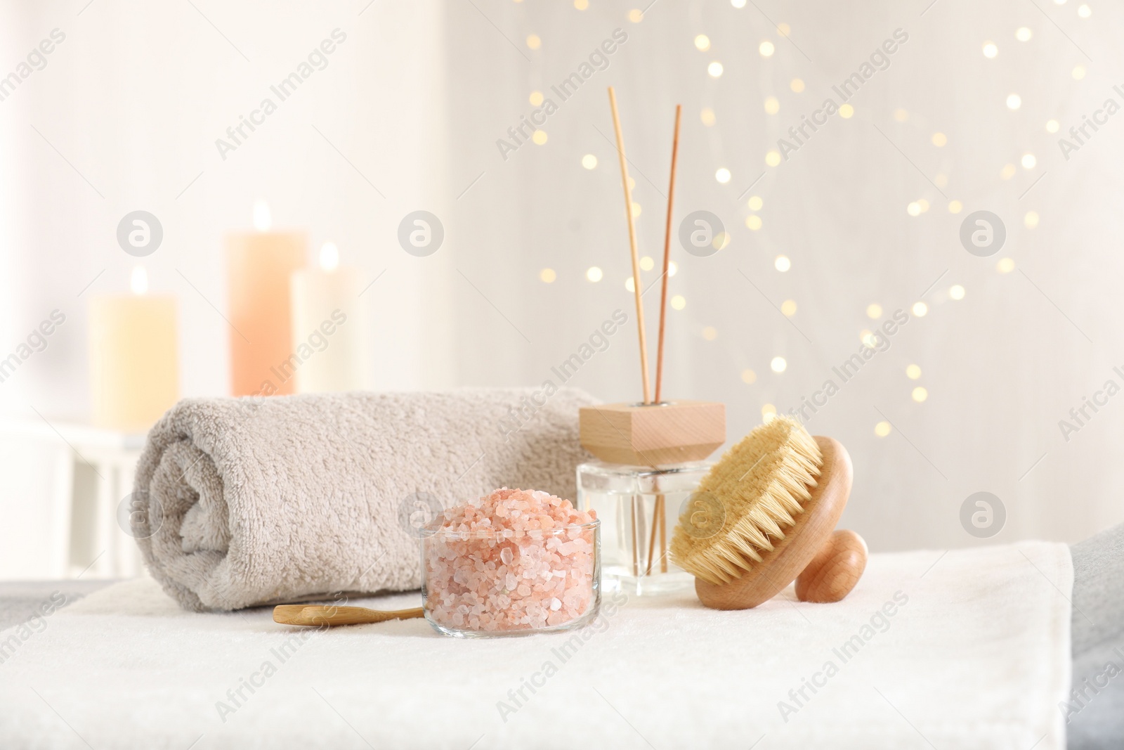 Photo of Spa composition. Sea salt, brush, towel and reed air freshener on soft surface