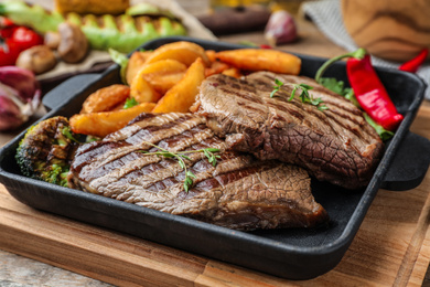 Photo of Delicious beef steaks served on wooden table, closeup