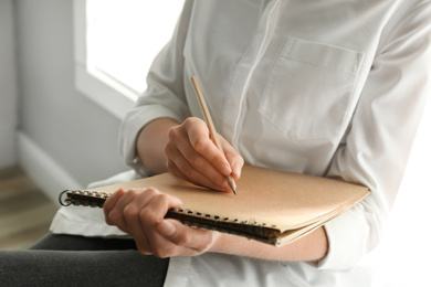 Woman drawing with pencil in notepad, closeup