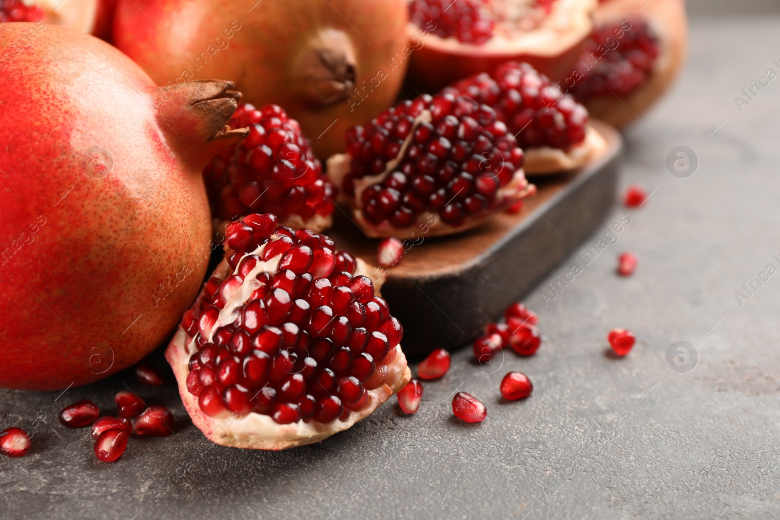 Photo of Delicious ripe pomegranates on grey table, closeup