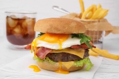 Photo of Delicious burger with fried egg on white table, closeup