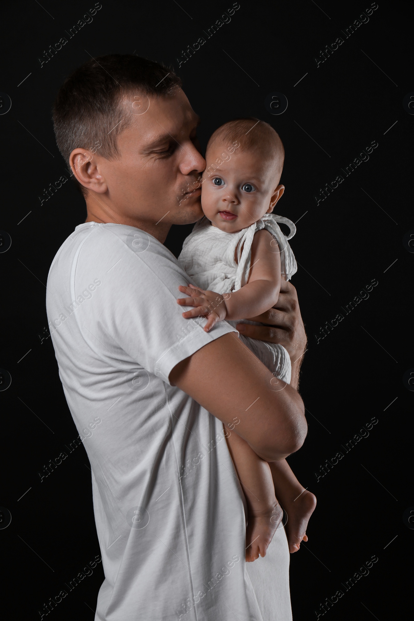 Photo of Happy father with his little baby on black background