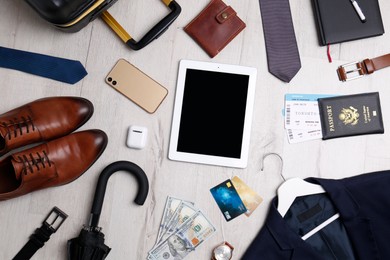 Business trip stuff on light wooden surface, flat lay