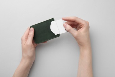 Woman holding business card holder with blank cards on light grey background, top view
