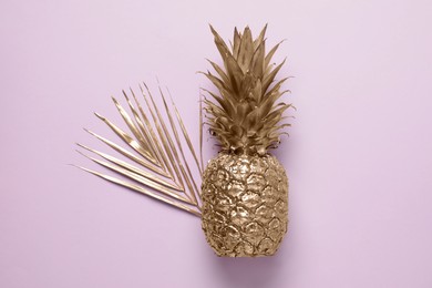 Photo of Golden pineapple and palm leaf on pink background, top view