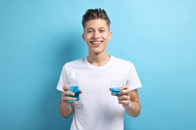 Young man with mouthwash on light blue background