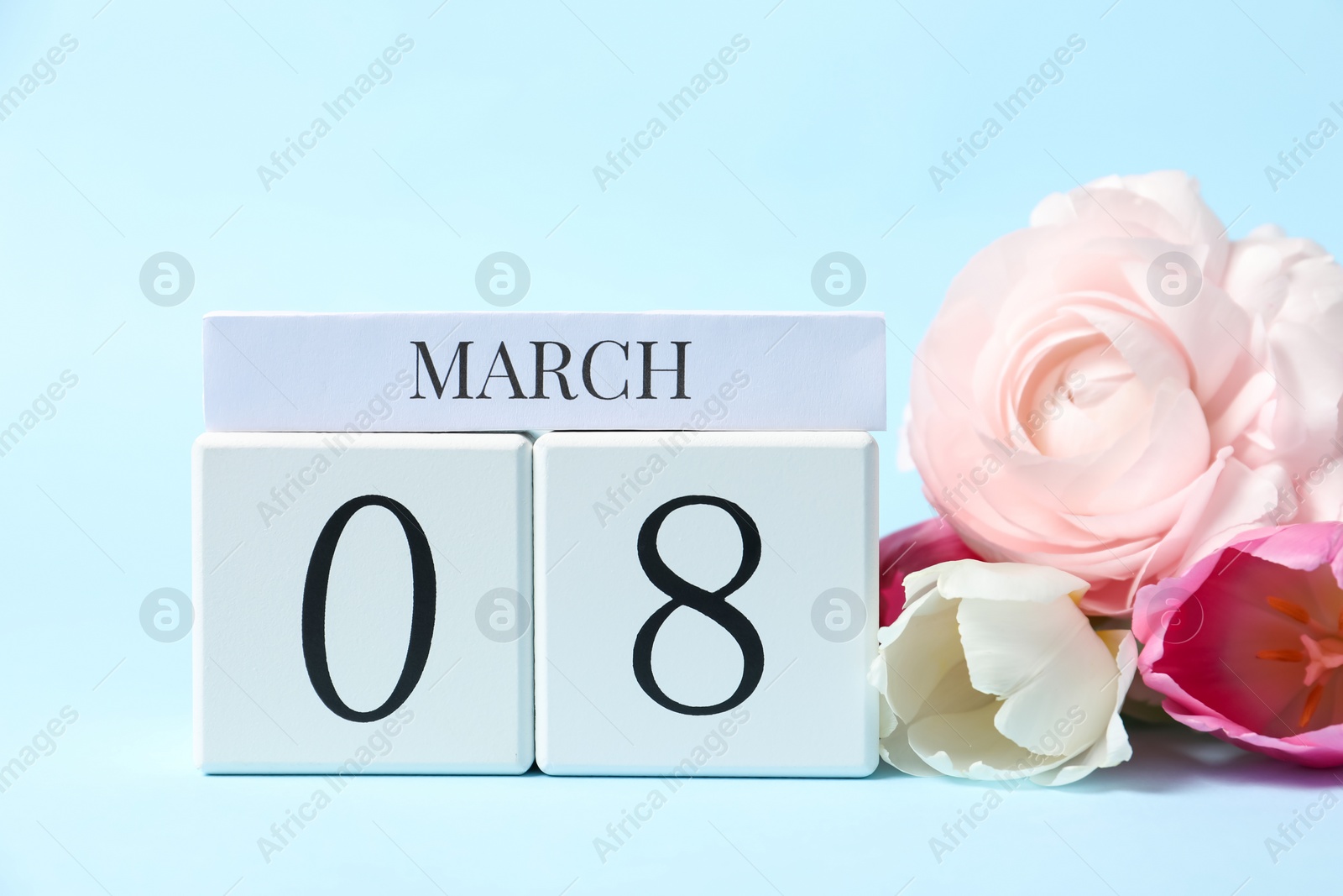 Photo of International Women's day - 8th of March. Wooden block calendar and beautiful flowers on light blue background