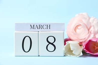 Photo of International Women's day - 8th of March. Wooden block calendar and beautiful flowers on light blue background