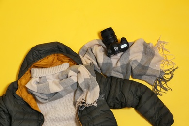 Set of warm clothes and camera on color background, flat lay. Winter vacation
