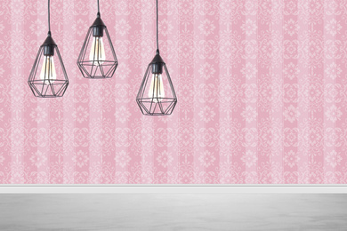 Stylish pendant lamps hanging near pink wall in room