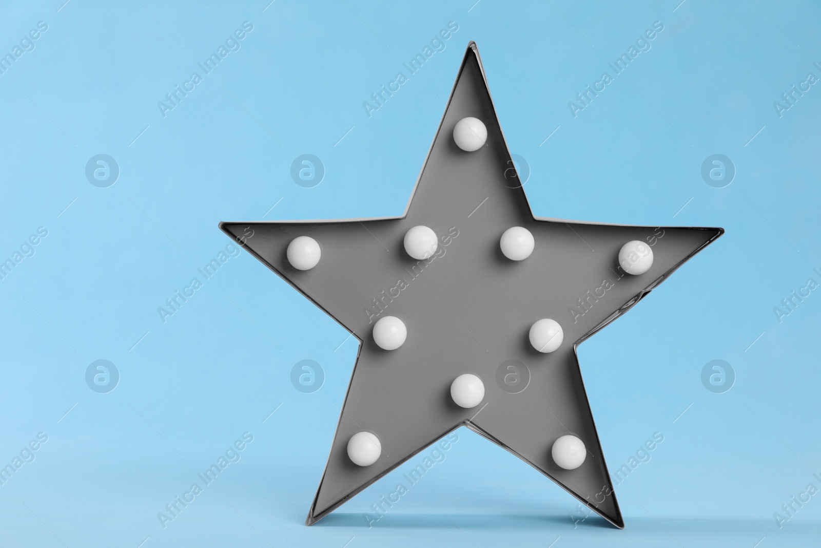 Photo of Stylish star shaped night lamp on light blue background