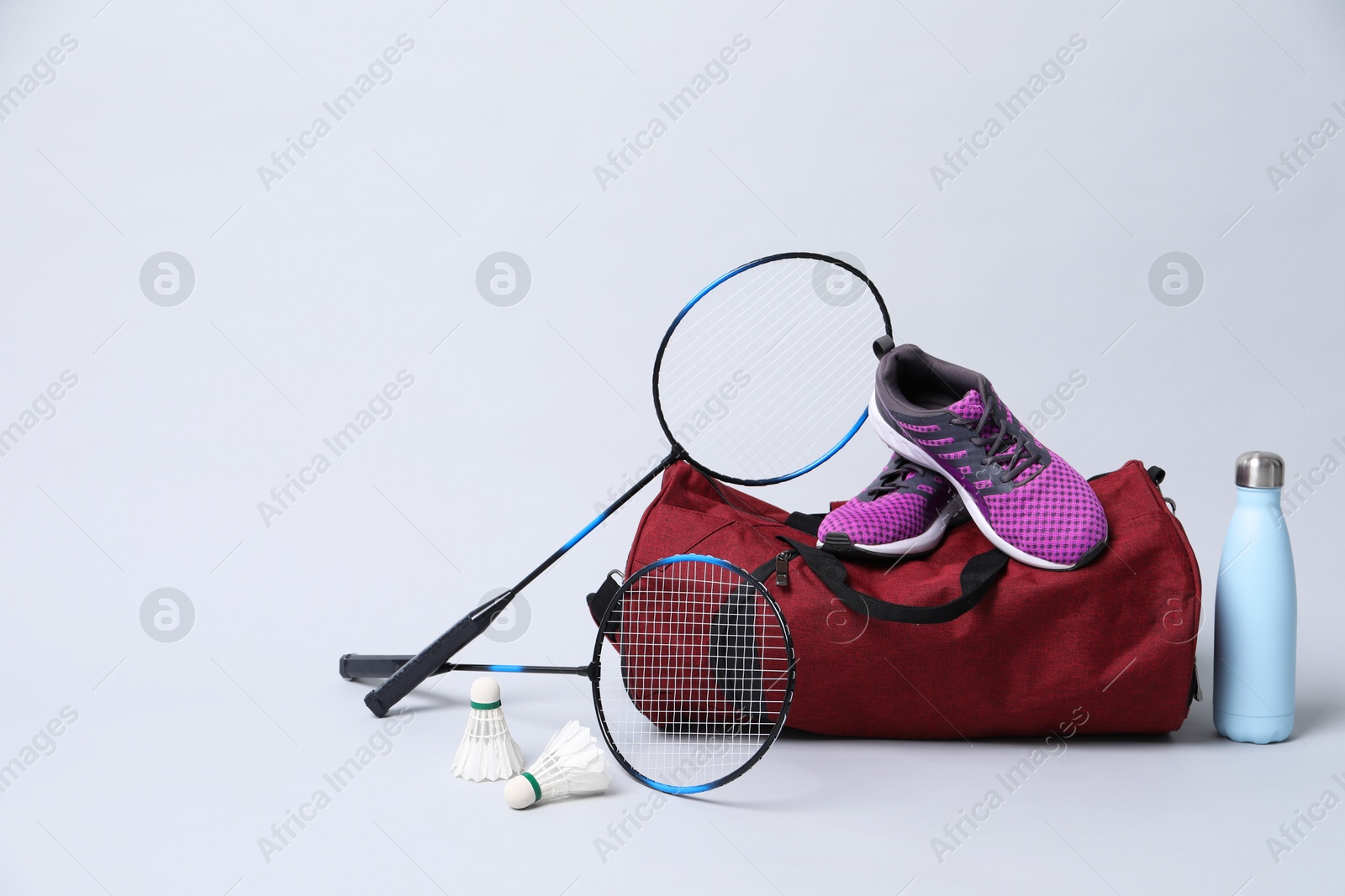 Photo of Badminton set, bag, sneakers and bottle on gray background, space for text