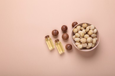 Photo of Delicious organic Macadamia nuts and cosmetic oil on beige background, flat lay. Space for text