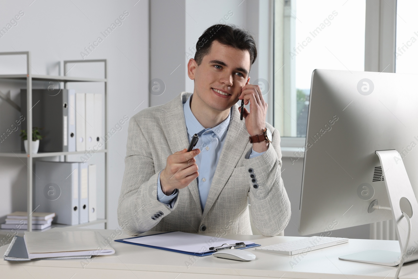 Photo of Businessman talking on phone while working in office