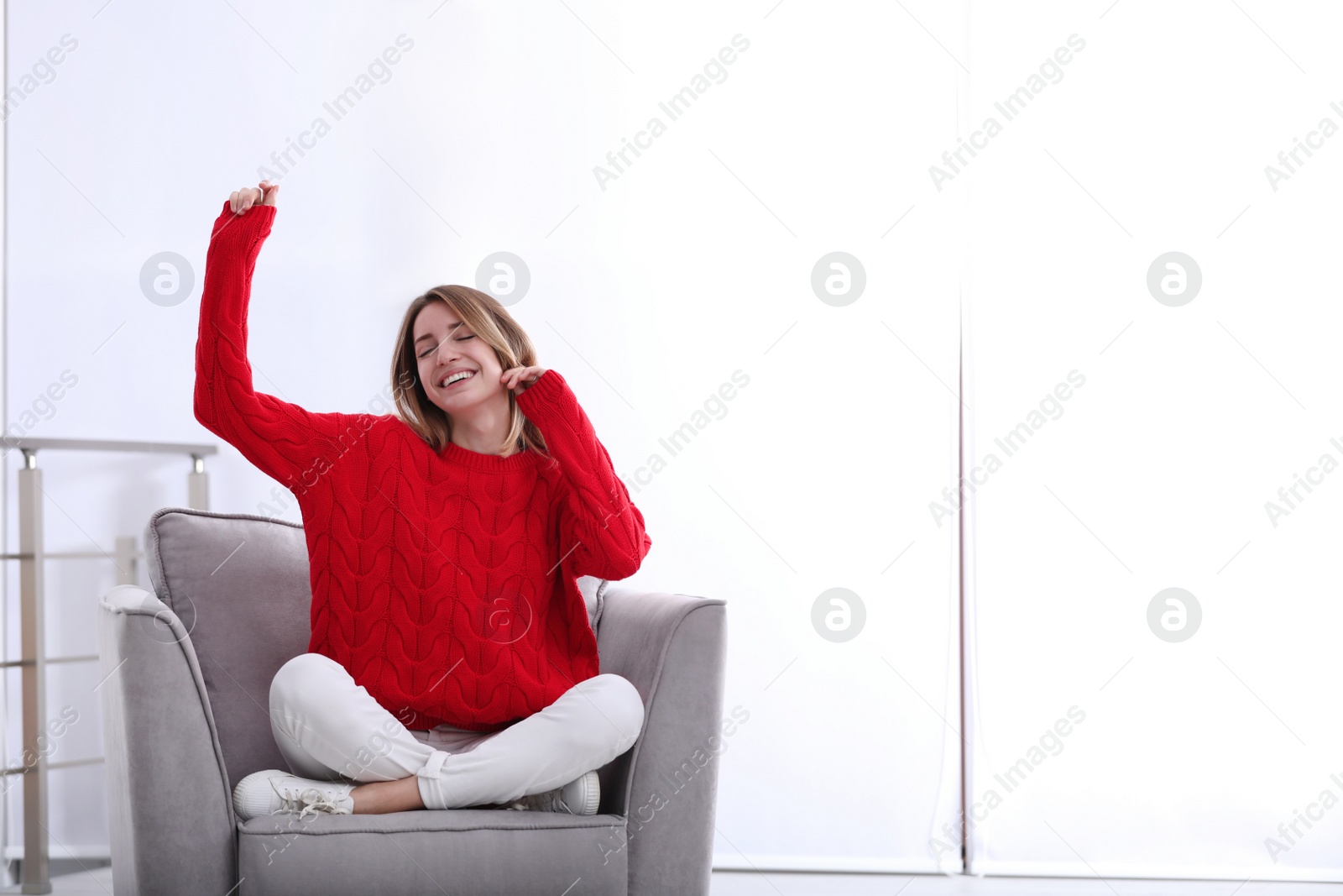 Photo of Emotional young woman sitting in armchair indoors. Space for text