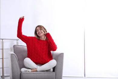 Photo of Emotional young woman sitting in armchair indoors. Space for text