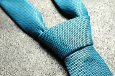 Photo of One blue necktie on grey textured background, closeup
