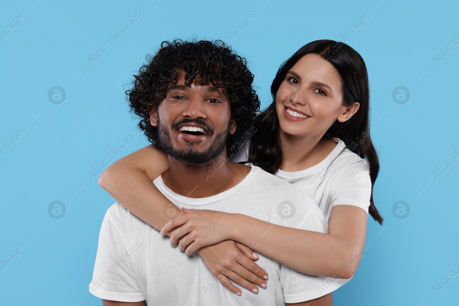 Photo of International dating. Happy couple hugging on light blue background