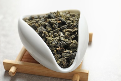 Photo of Chahe of Tie Guan Yin oolong tea leaves on light background, closeup