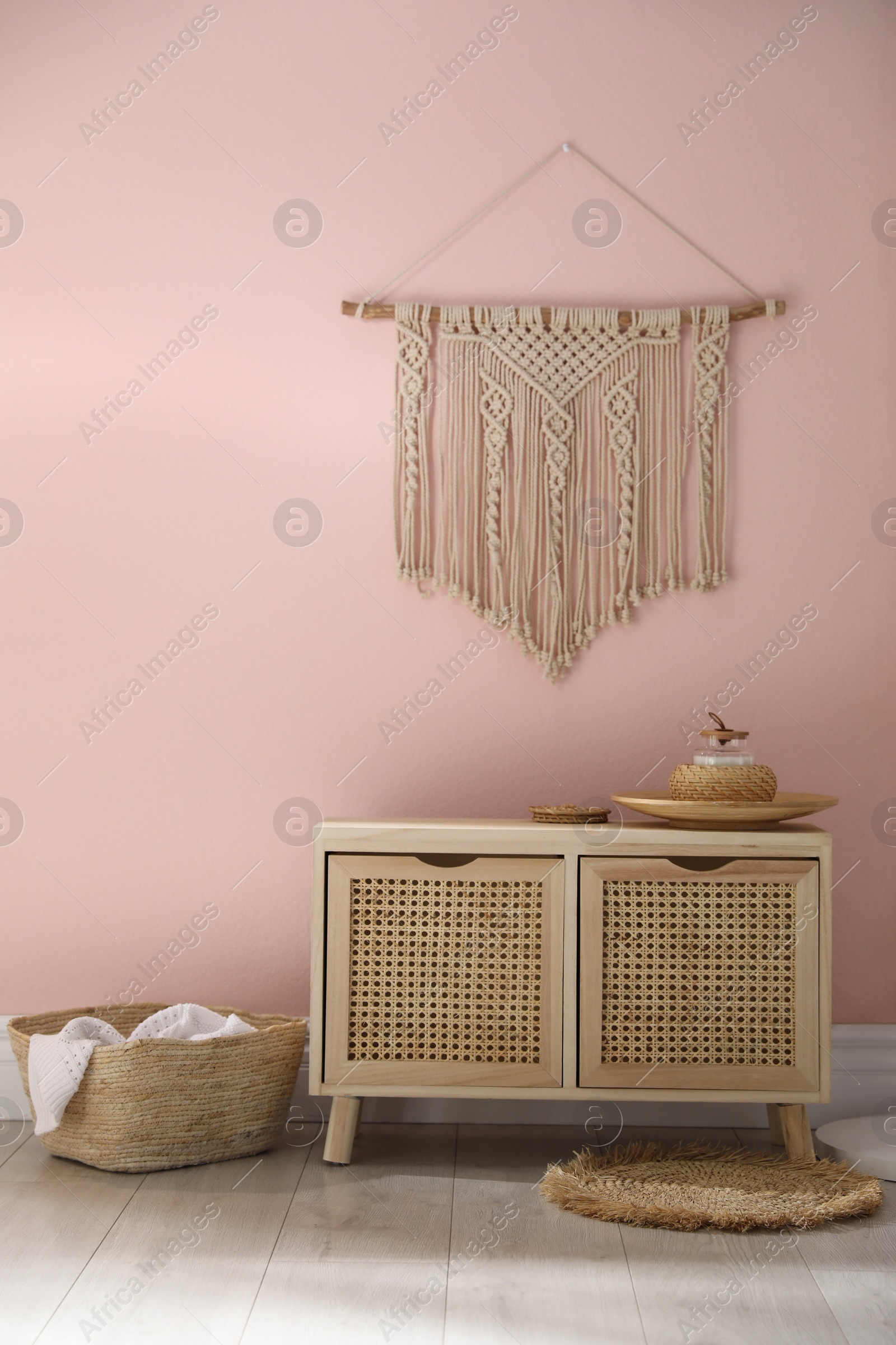 Photo of Wooden commode near pink wall in room. Interior design