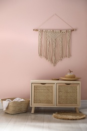 Photo of Wooden commode near pink wall in room. Interior design