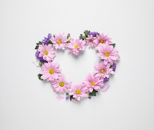 Photo of Heart shaped frame made of beautiful chamomile flowers on white background, top view. Space for text