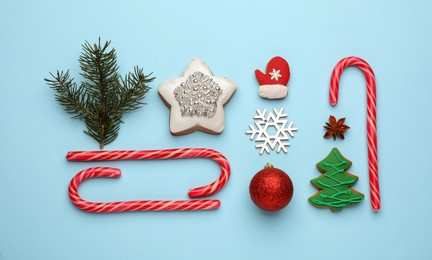 Flat lay composition with sweet candy canes and Christmas decor on light blue background