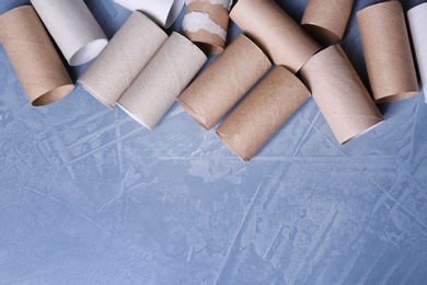Photo of Empty toilet paper rolls and space for text on color background, top view