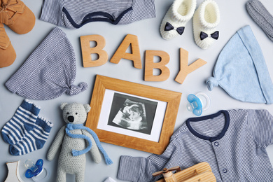 Photo of Flat lay composition with child's clothes, ultrasound photo and word Baby on light background