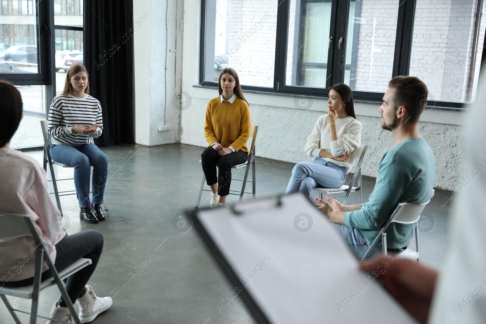 Photo of Psychotherapist working with patients in group therapy session indoors