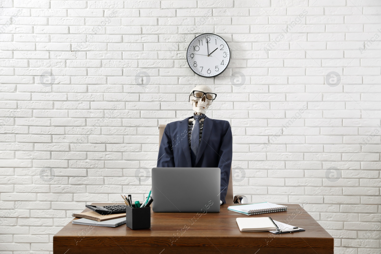 Photo of Human skeleton in suit using laptop at table in office