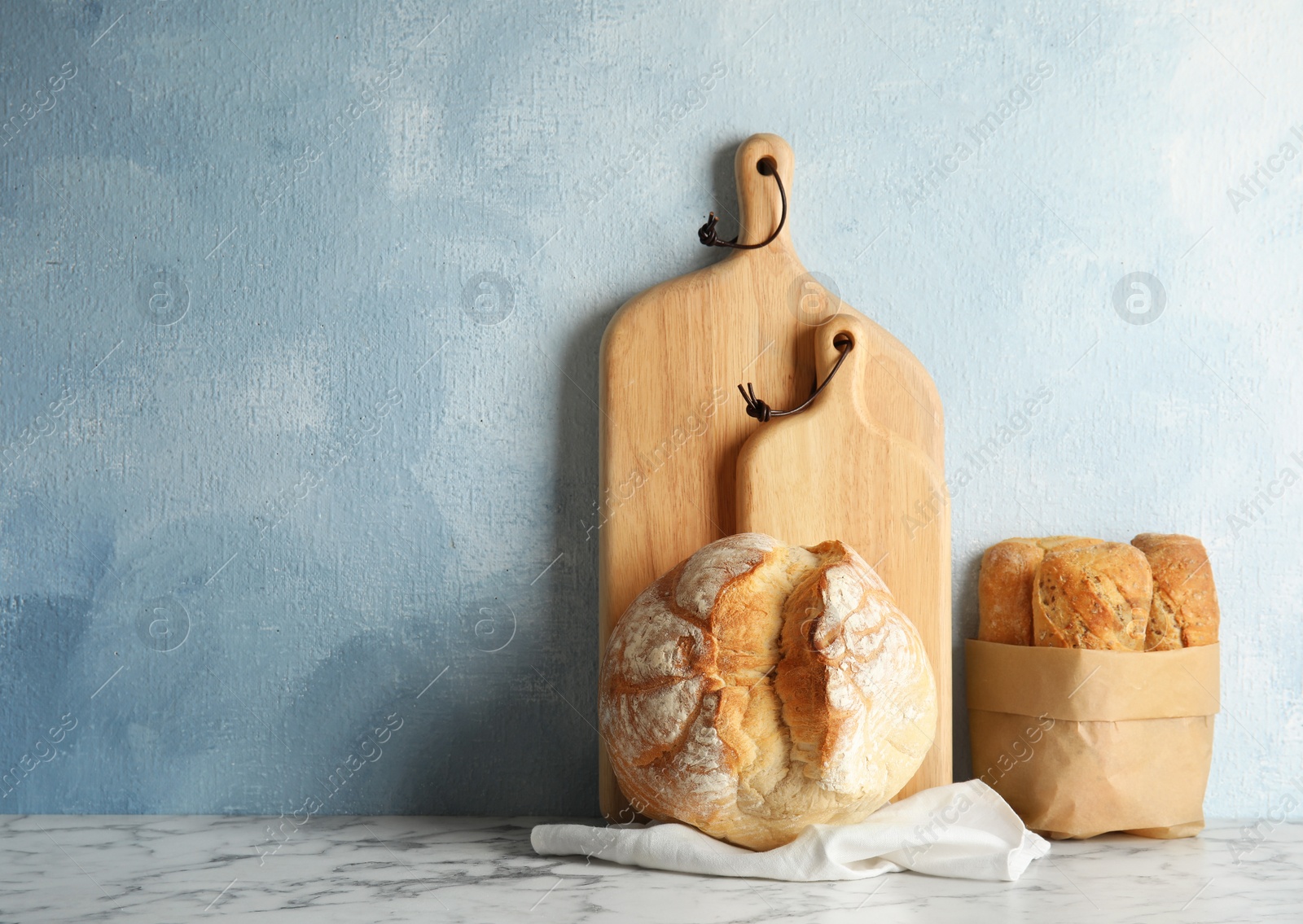 Photo of Composition with fresh bread on table near color wall. Space for text