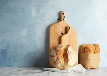 Photo of Composition with fresh bread on table near color wall. Space for text