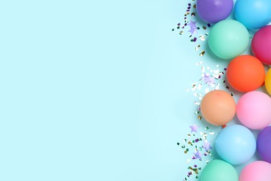 Photo of Flat lay composition with balloons and confetti on light blue background, space for text. Birthday decor