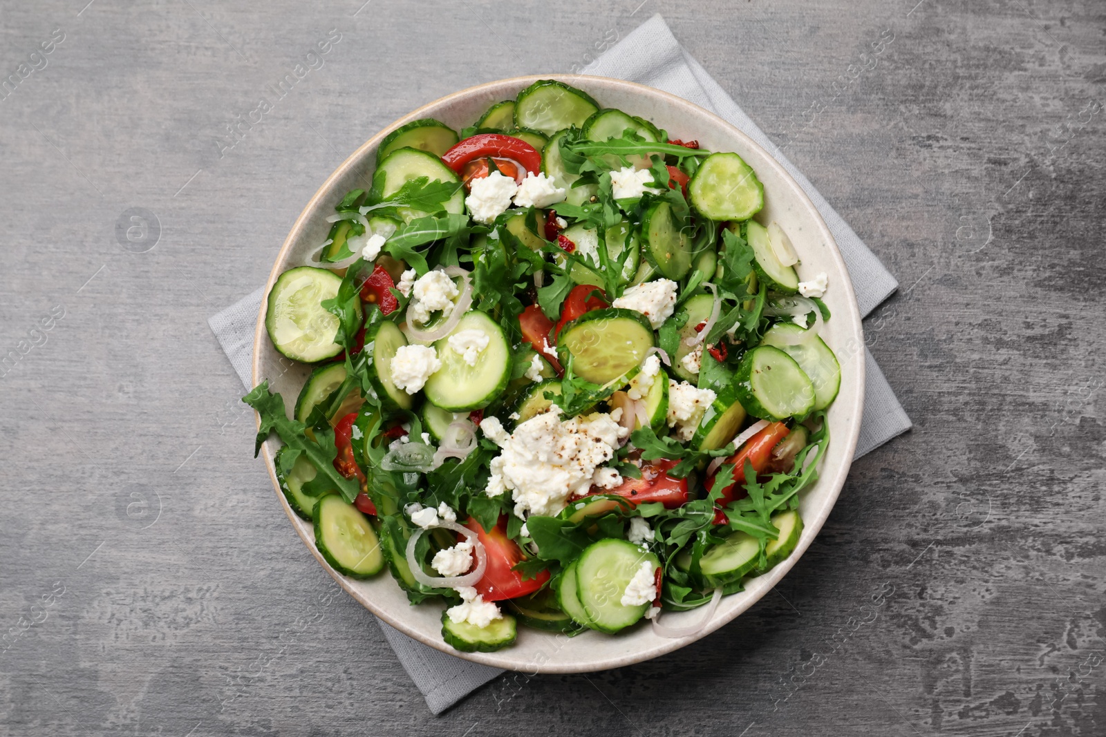 Photo of Plate of delicious cucumber salad on grey table, top view