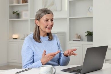 Happy woman having video chat via laptop at table indoors