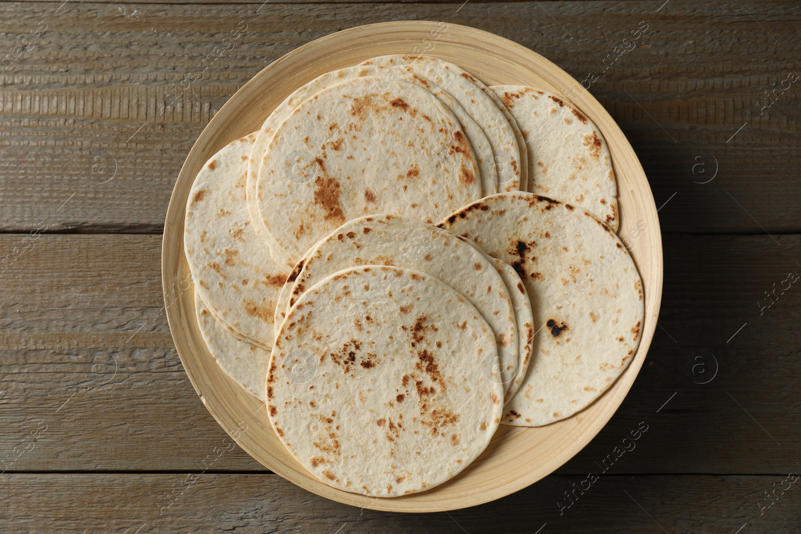 Photo of Many tasty homemade tortillas on wooden table, top view