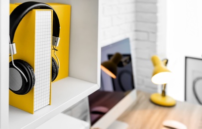 Workplace with folder and headphones on shelf over desk at home