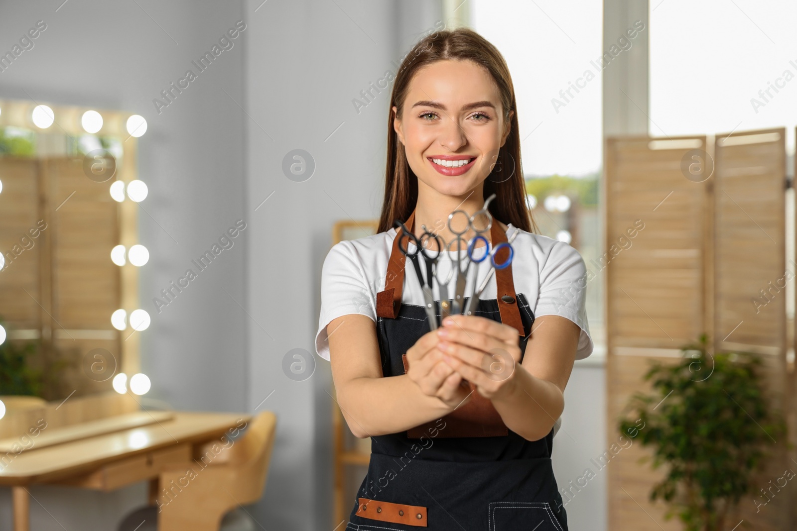 Photo of Portrait of happy hairdresser with professional scissors in beauty salon