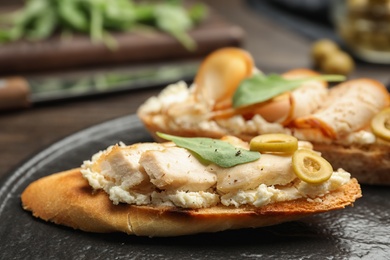 Slate plate of delicious chicken bruschettas on table, closeup