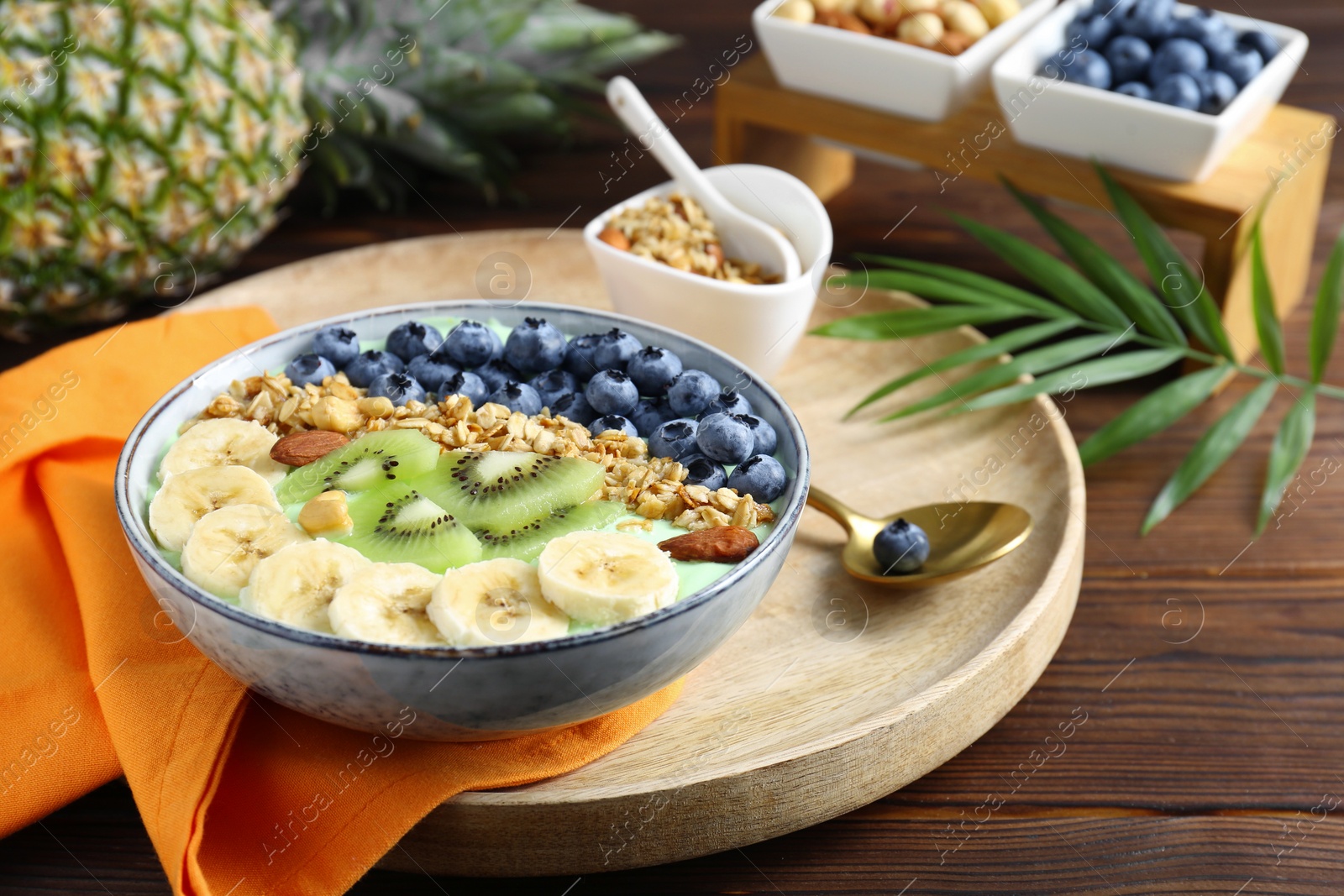 Photo of Tasty smoothie bowl with fresh fruits and oatmeal served on wooden table