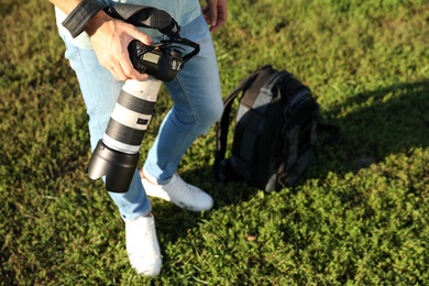 Photo of Young male photographer holding professional camera outdoors