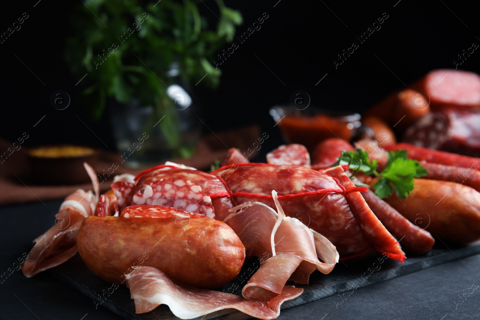 Photo of Different types of sausages served on black table, closeup