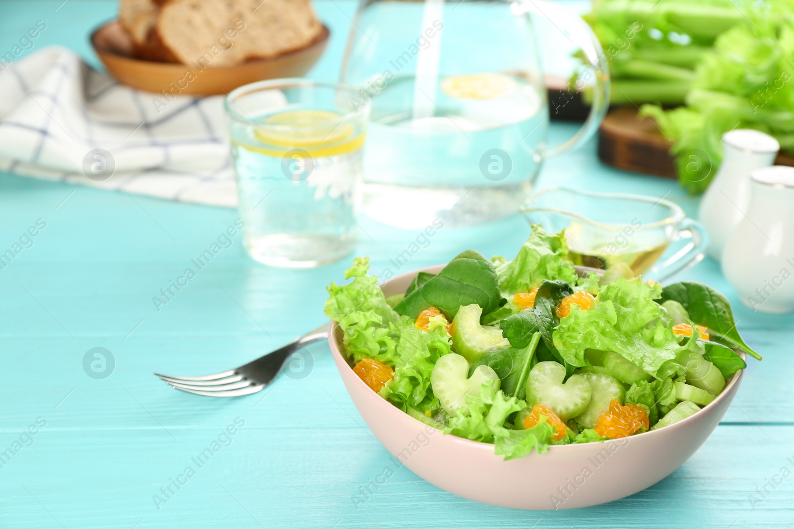 Photo of Delicious fresh celery salad on light blue wooden table. Space for text