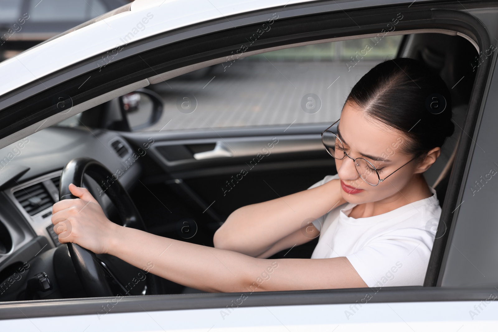 Photo of Young woman suffering from neck pain in her car