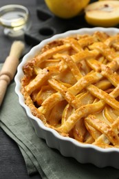 Photo of Tasty homemade quince pie and fresh fruits on black wooden table, closeup