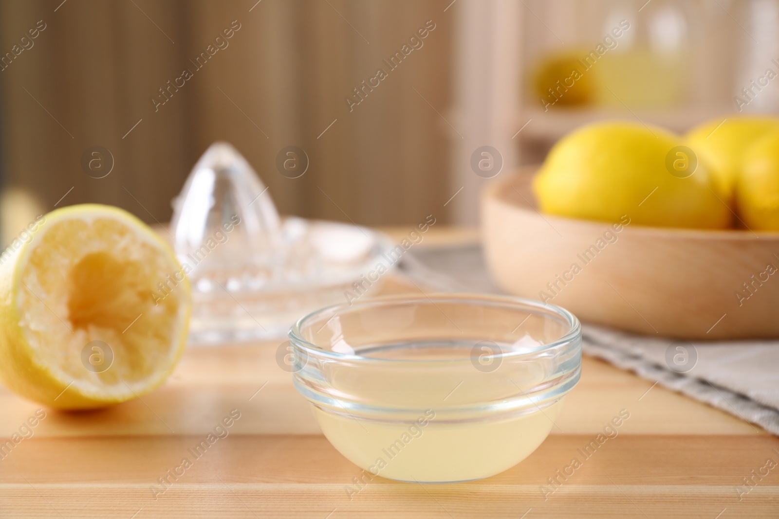 Photo of Freshly squeezed lemon juice in glass bowl on wooden table. Space for text