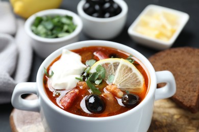 Meat solyanka soup with sausages, olives and vegetables in bowl served on table, closeup