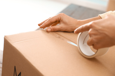 Woman packing box at table, closeup. Moving day